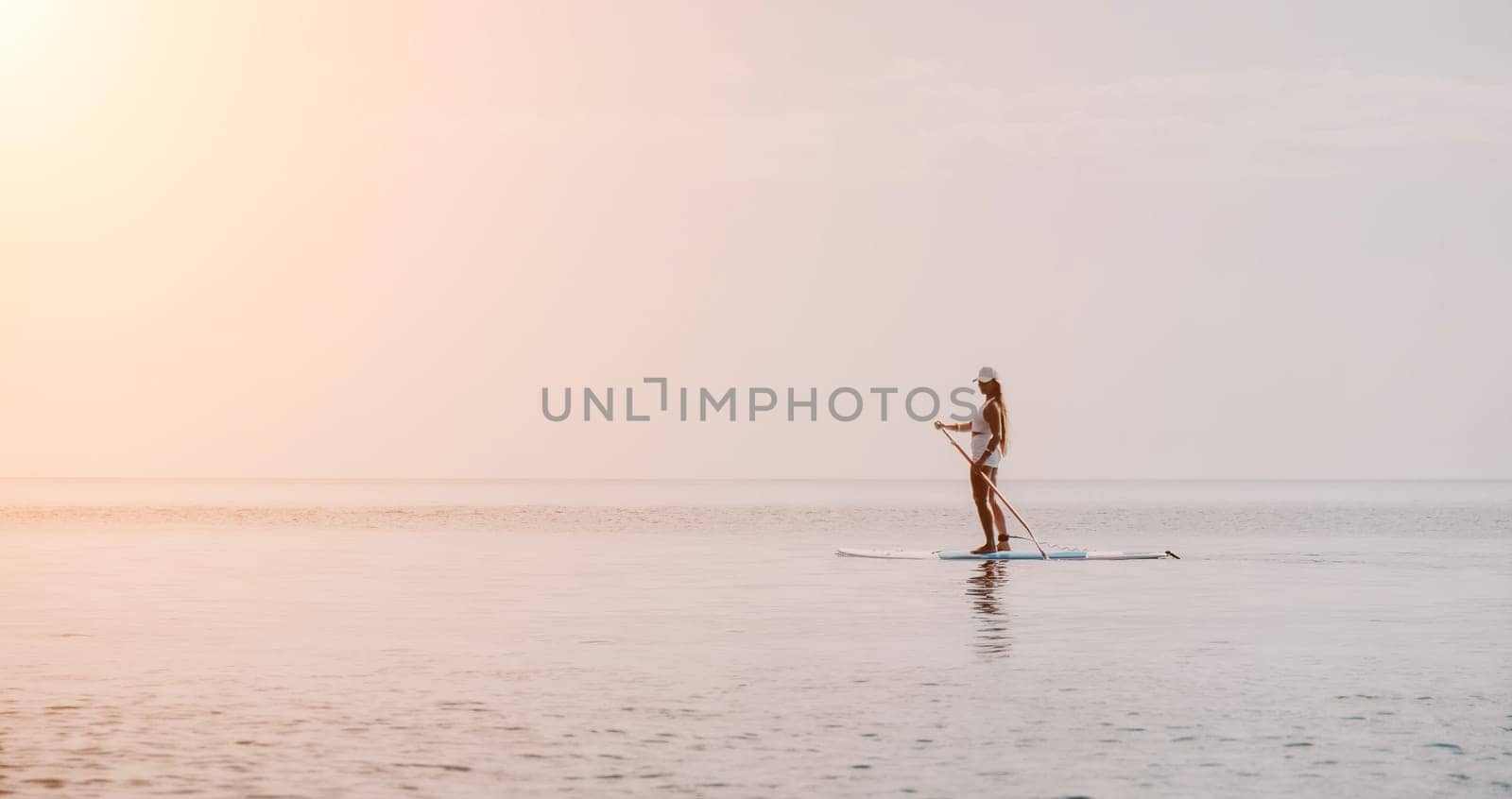 Close up shot of beautiful young caucasian woman with black hair and freckles looking at camera and smiling. Cute woman portrait in a pink bikini posing on a volcanic rock high above the sea