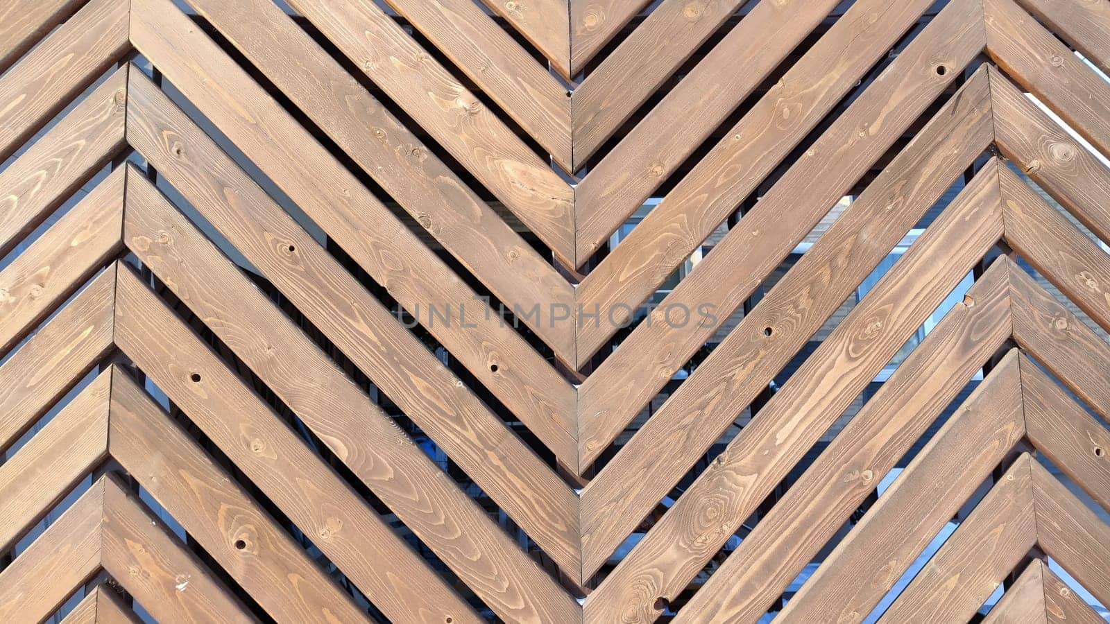 Fence made of wooden slats with a pattern in the shape of fir tree as a Location, Background, texture, copy of space, frame. Abstract natural graphic resource