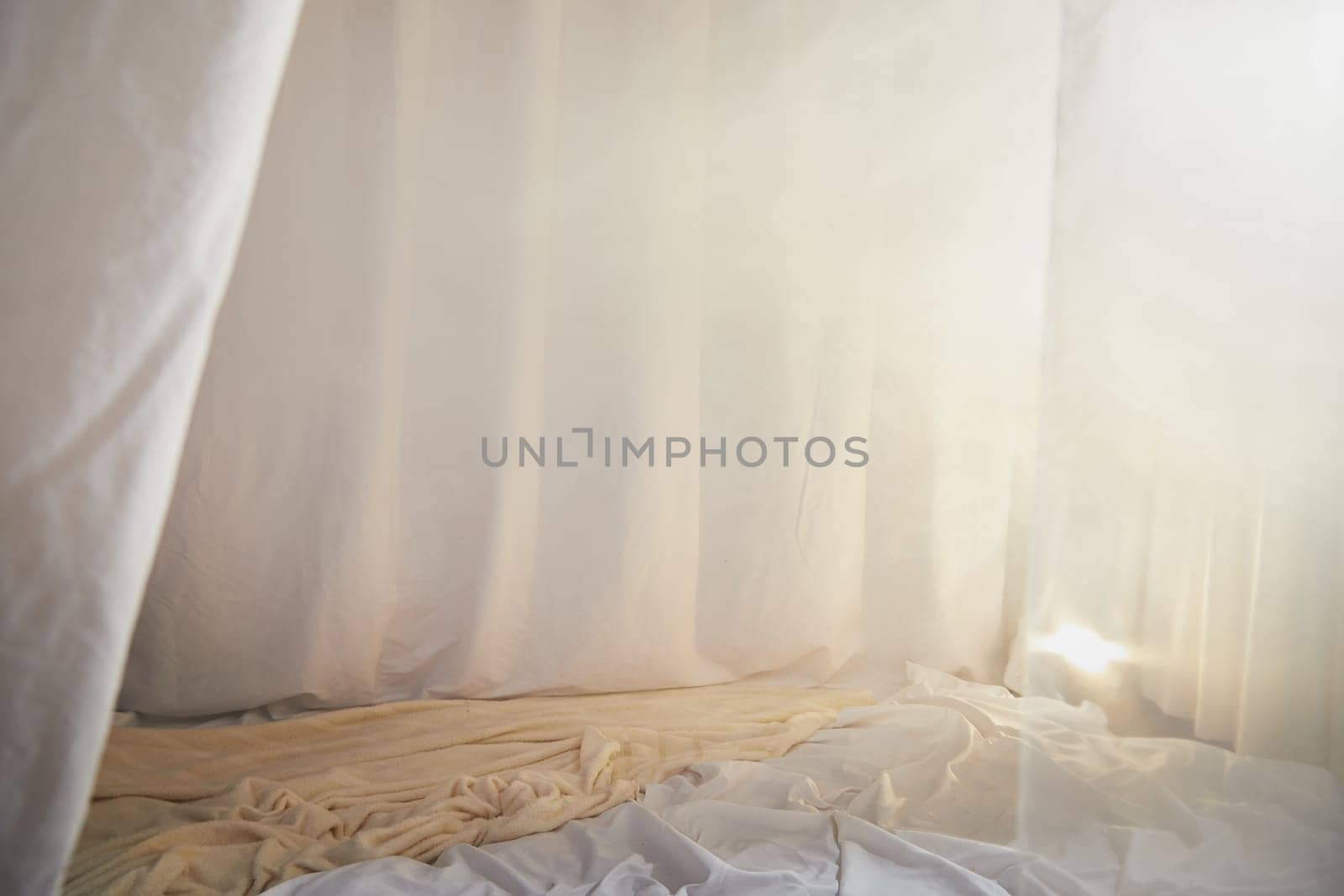 Light, soft transparent curtains in room. Canopy around bed with gentle light and blurring in evening. Boudoir. Concept of comfort in house and bedroom. Location and background for the photo shoot