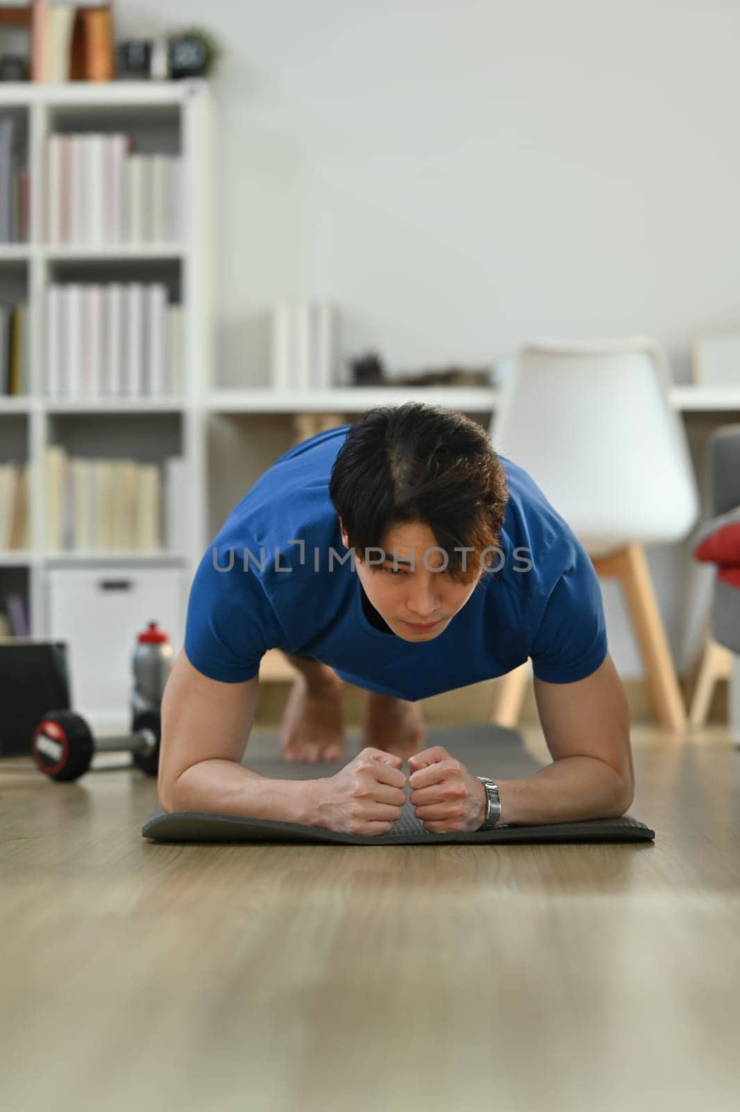 Sporty asian man wearing doing plank position while exercising in cozy home interior. Healthy lifestyle, sport and motivation concept.