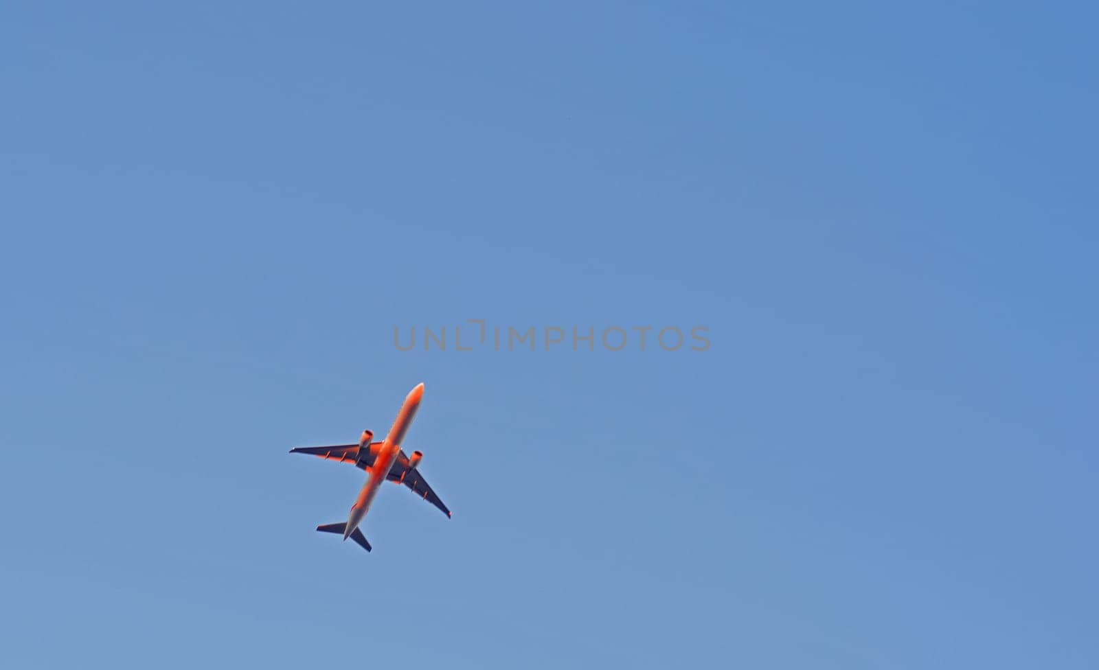The passenger airplane is flying far away in blue sky