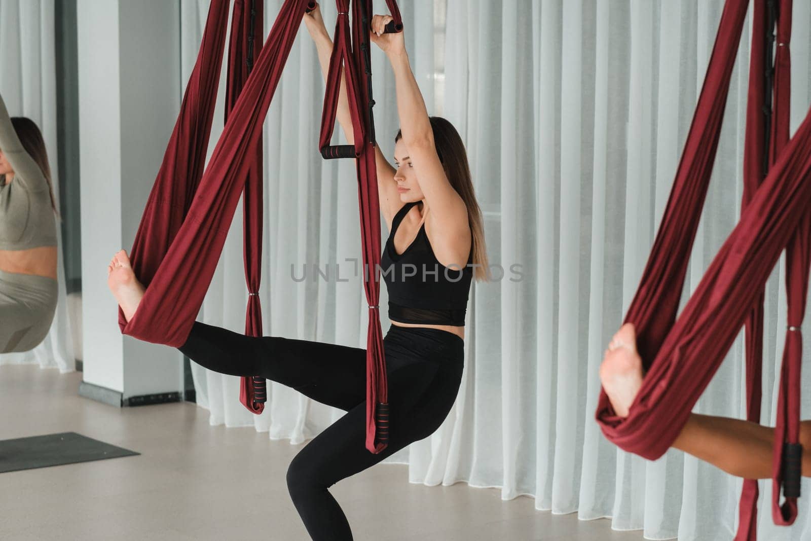 A group of women play sports on hanging hammocks. Fly yoga in the gym.