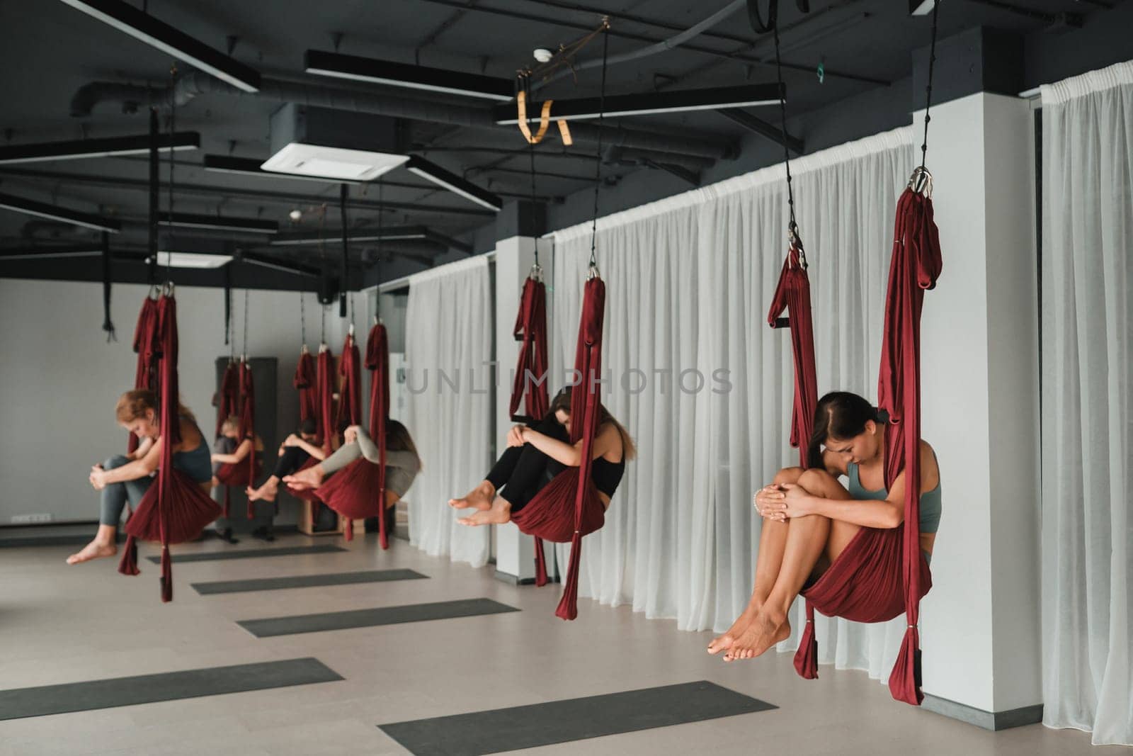 A group of women play sports on hanging hammocks. Fly yoga in the gym.