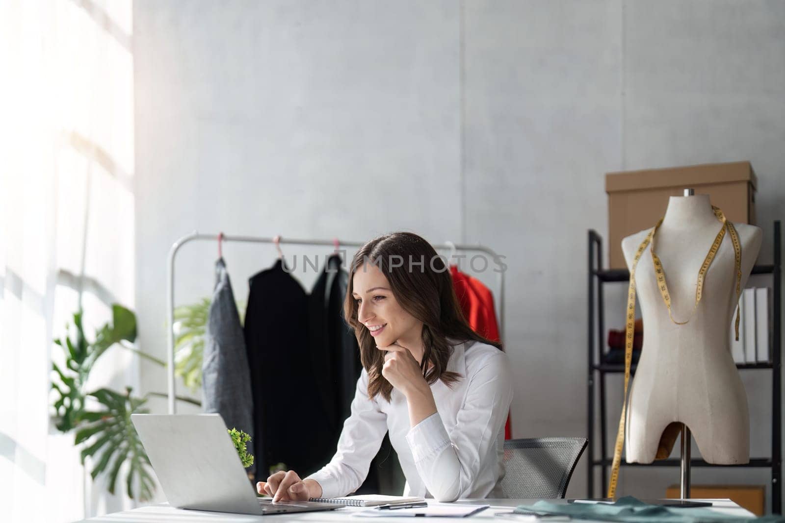 Responding on business e-mail. Beautiful young Fashion designer woman working using computer and smiling while siting in home.
