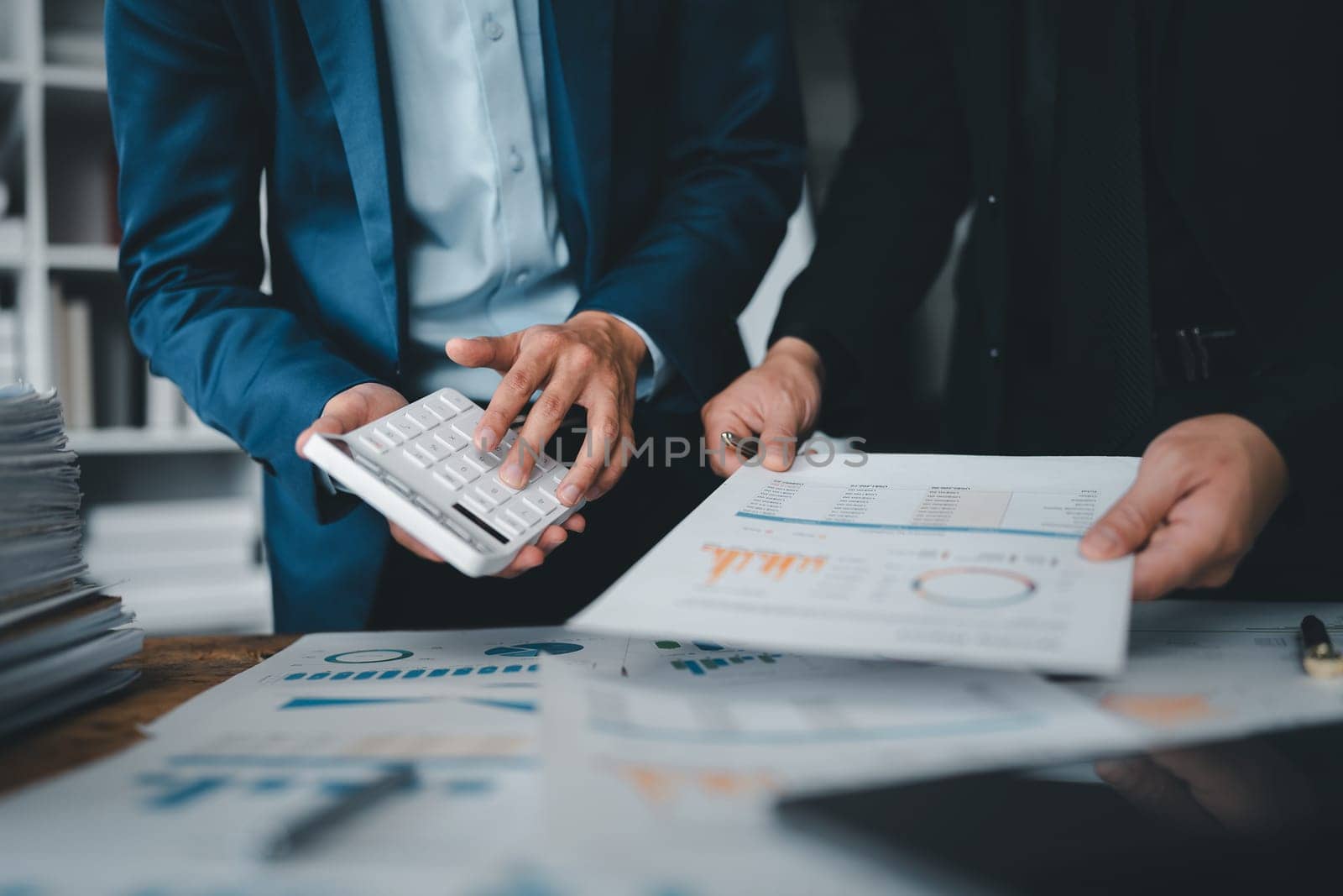 Accountant checking financial statement or counting by calculator income for tax form, Business woman sitting and working with colleague discussing the desk in office. Audit concept by Manastrong