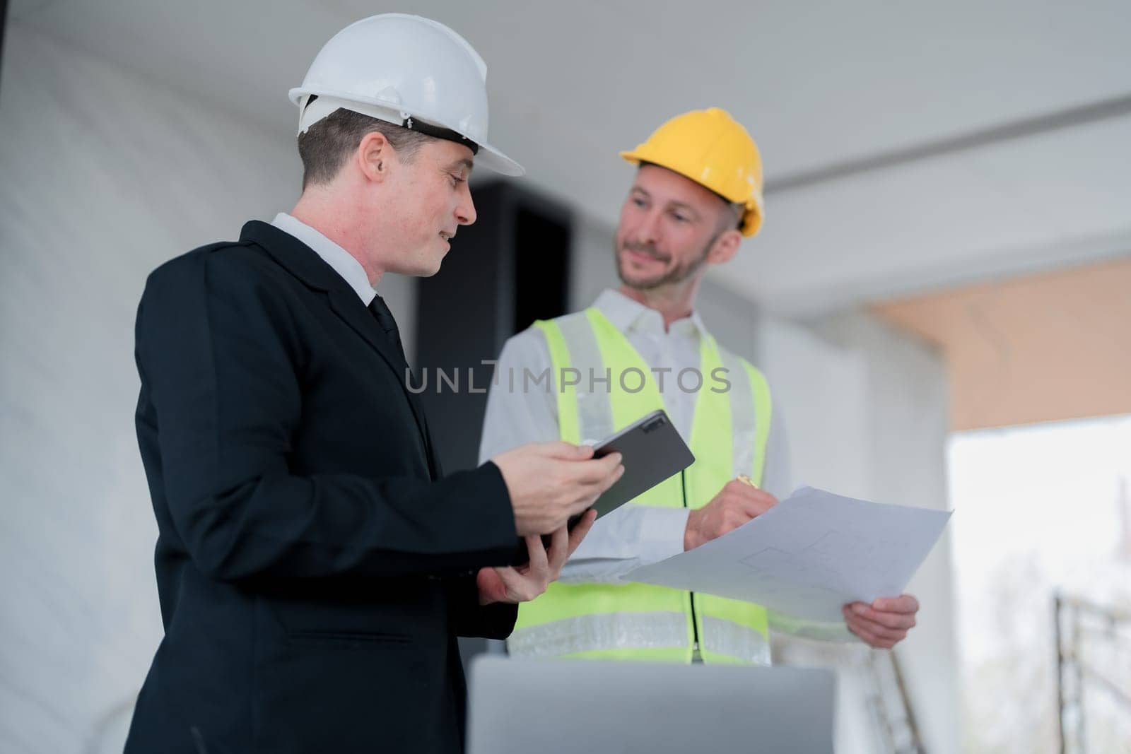 multi ethnic engineer brainstorming and measuring for cost estimating on blueprint and floor plan drawings about design architectural and engineering for houses and buildings.