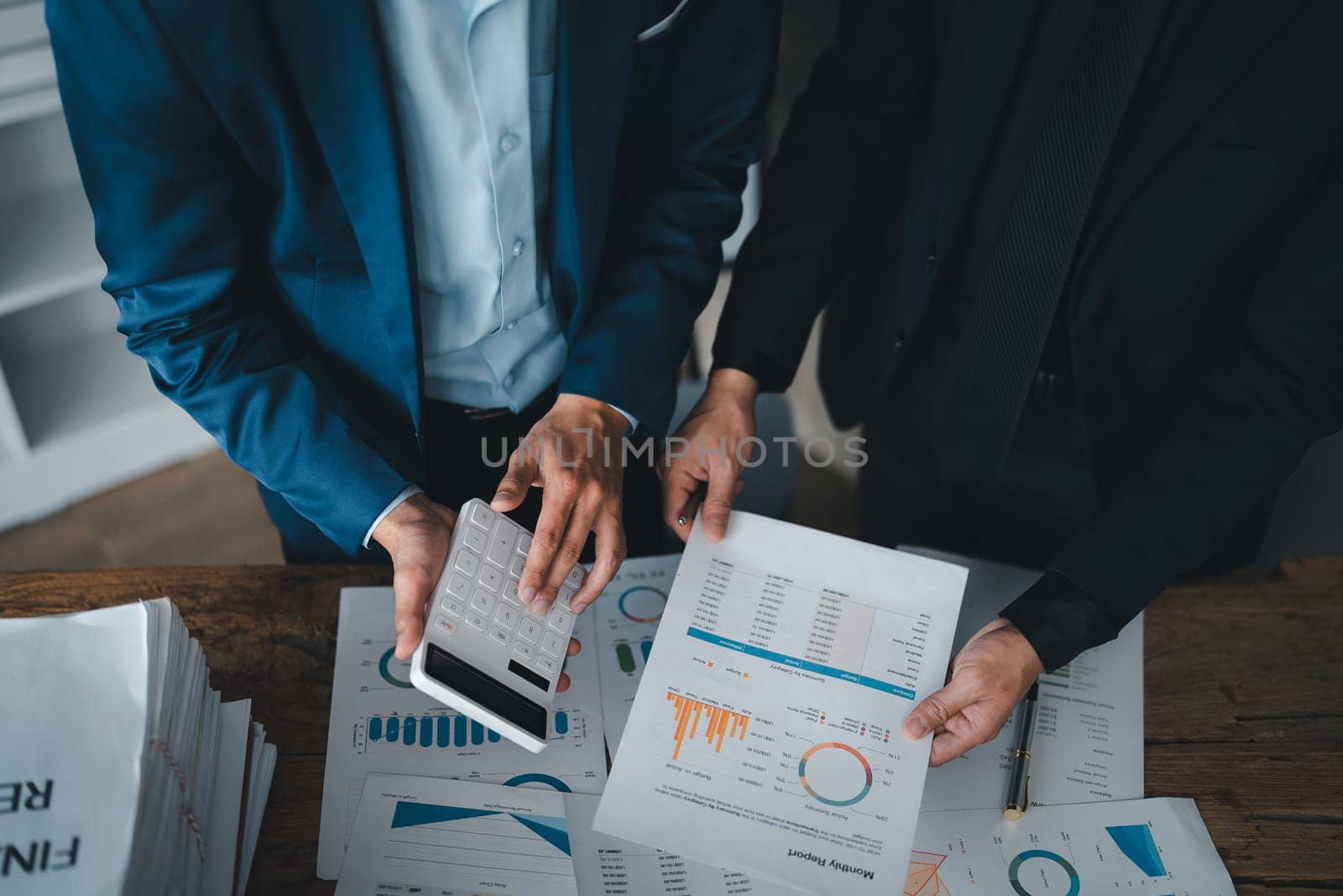 Accountant checking financial statement or counting by calculator income for tax form, Business woman sitting and working with colleague discussing the desk in office. Audit concept by Manastrong