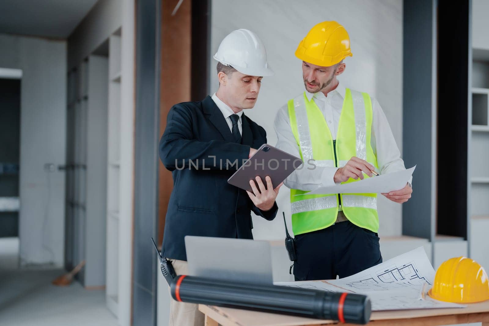 multi ethnic engineer brainstorming and measuring for cost estimating on blueprint and floor plan drawings about design architectural and engineering for houses and buildings.