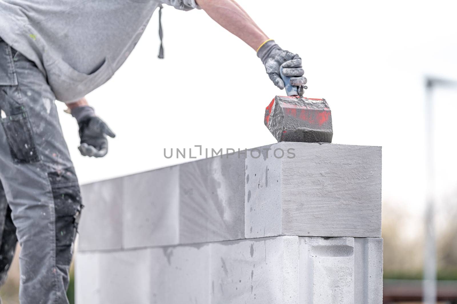 the mason applies glue to the concrete forms. construction of a wall of concrete bricks. High quality photo