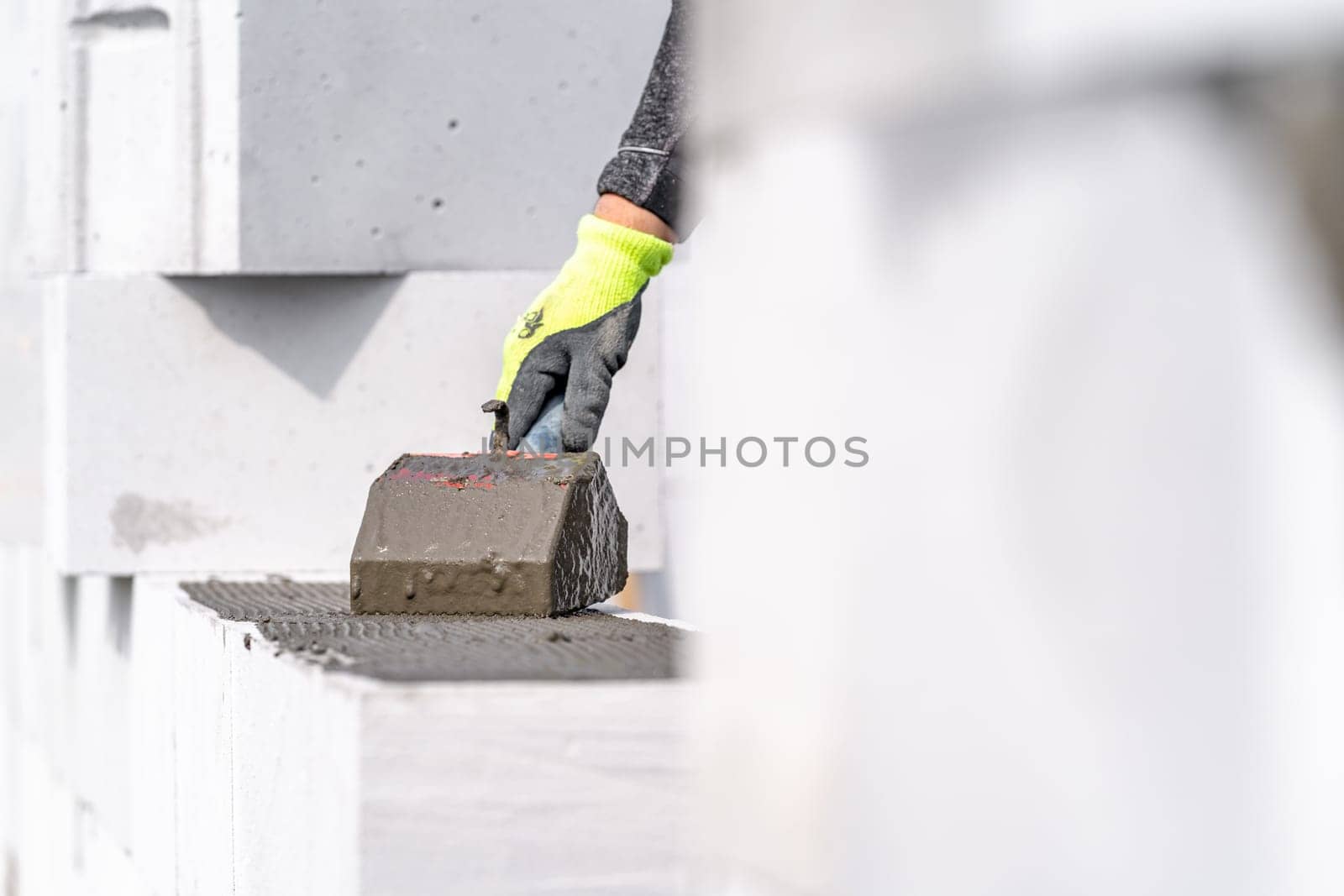 the mason applies glue to the concrete forms. construction of a wall of concrete bricks. High quality photo