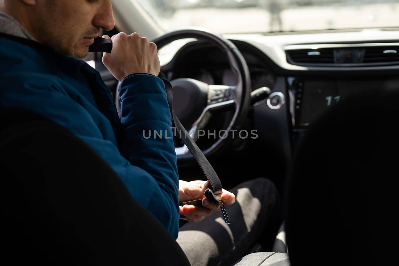 Men's hand fastens the seat belt of the car. Close your car seat belt while sitting inside the car before driving and take a safe journey. Closeup shot of male driver fastens seat belt. by Andelov13