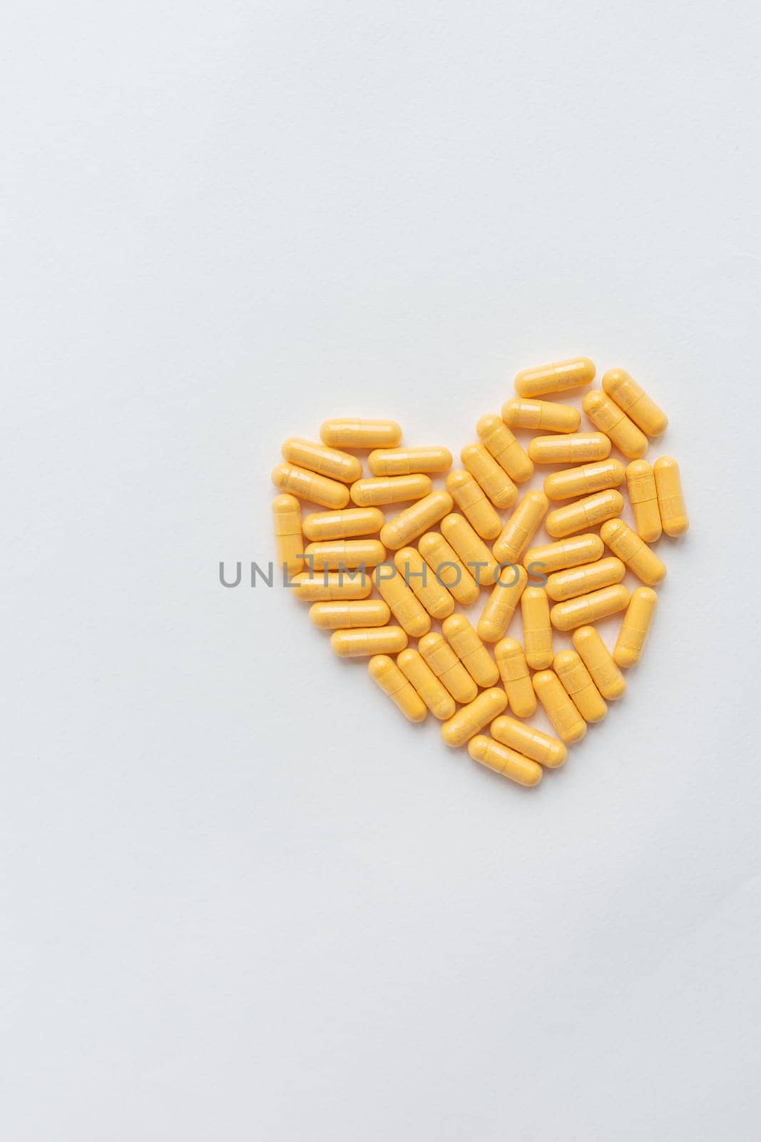 Yellow pills in the shape of a heart, health and heart problems. The concept of medicine and healthcare. Place for an inscription, vertical photo. by sfinks