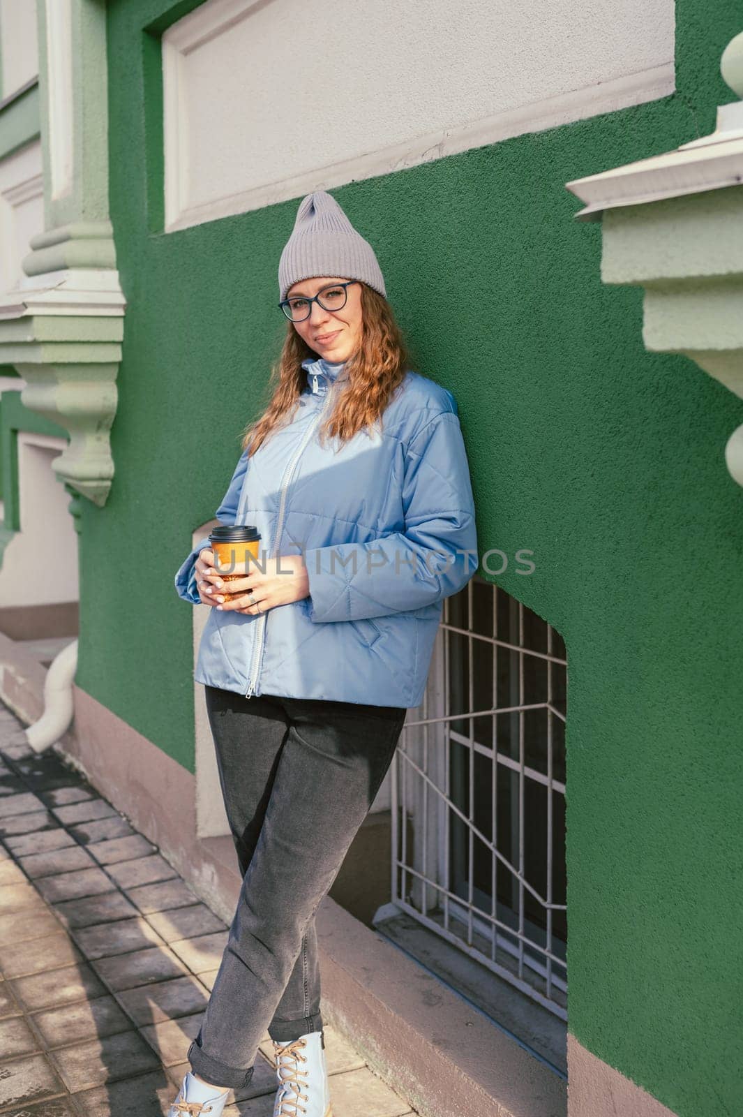 Portrait of a stylish woman in blue jacket with coffee cup. Spring outdoor portrait.
