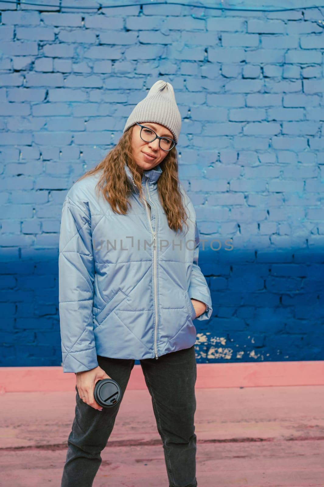 Portrait of a stylish woman in blue jacket with coffee cup. Spring outdoor portrait.