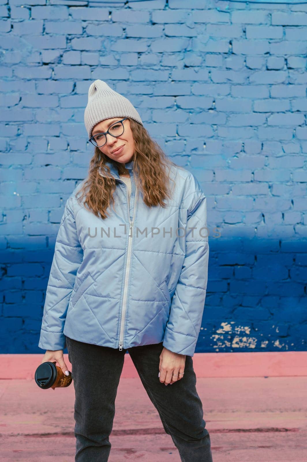 Portrait of a stylish woman in blue jacket with coffee cup. Spring outdoor portrait.