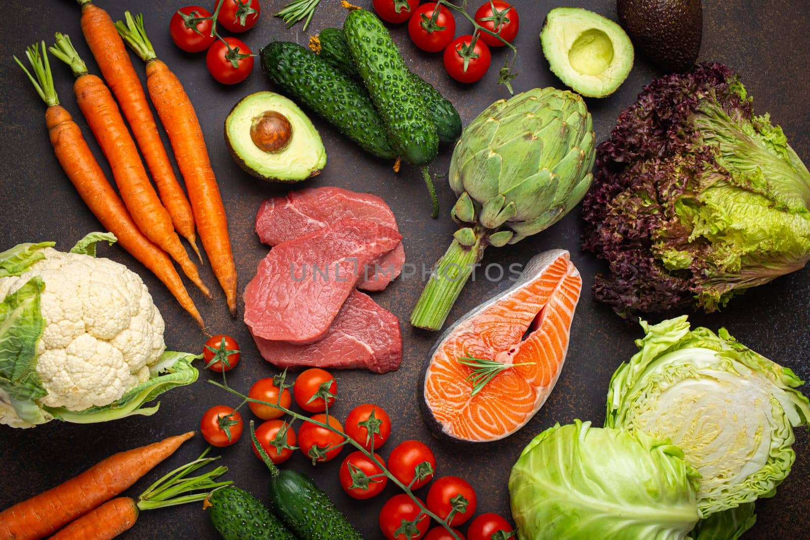 Assorted food raw products: vegetables, beef meat steak, fish salmon fillet on dark rustic brown stone table top view. Healthy food background, ingredients with vitamins concept, diet and nutrition