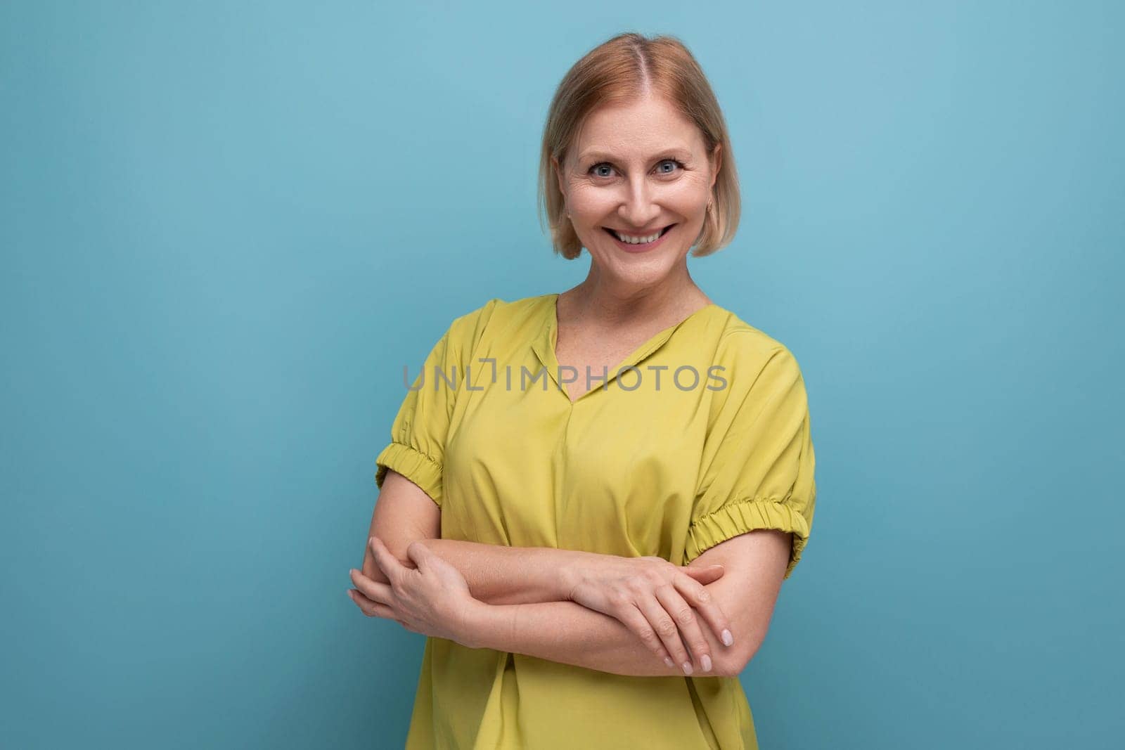 thoughtful blonde mature woman smiling and emotional on studio background.