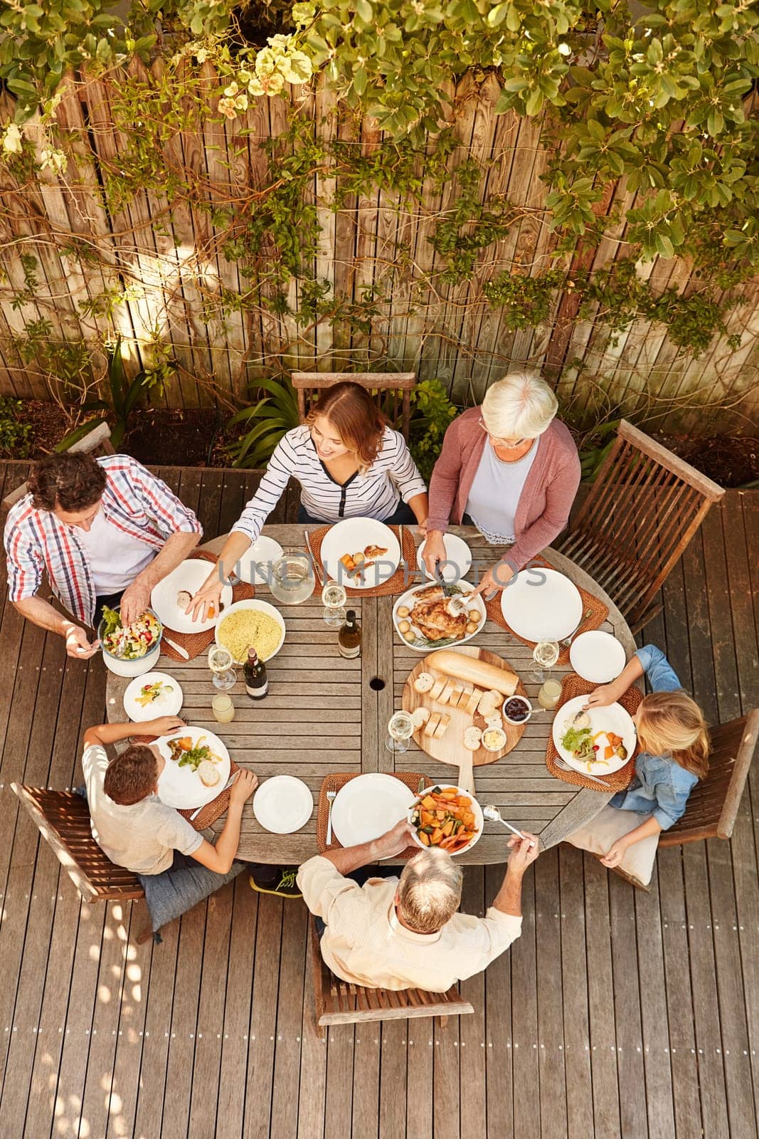 Reconnecting as a family over lunch. High angle shot of a family eating lunch outdoors. by YuriArcurs