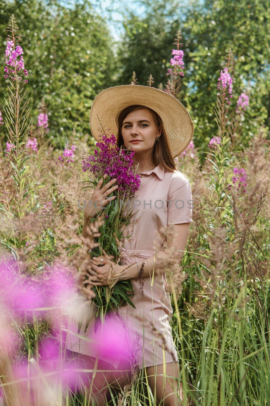 A young woman in nature with a bouquet of pink wild flowers. A bouquet of Ivan-tea in the hands of a woman.