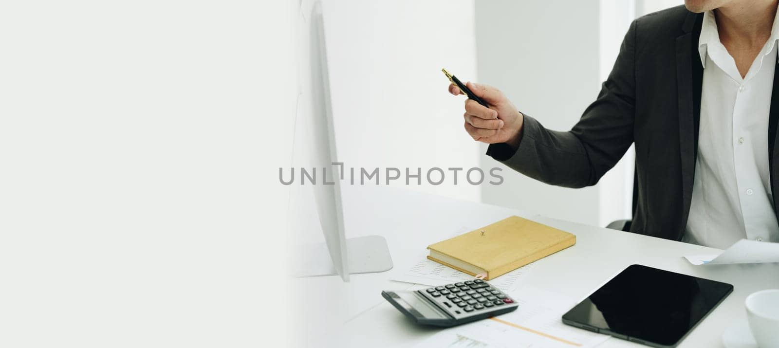 Portrait of a young Asian woman showing a smiling face as she uses his phone, computer and financial documents on her desk in the early morning hours by Manastrong