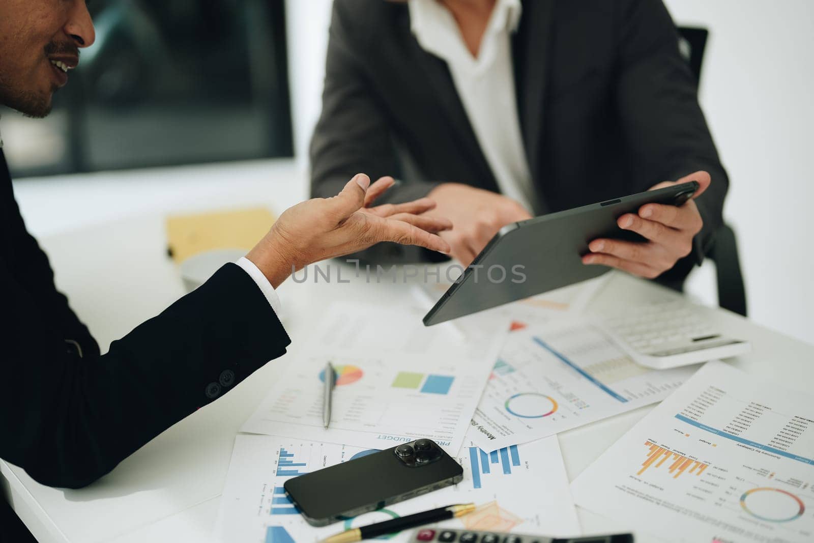 Two business men meeting to talking or discuss marketing work in workplace using paperwork, calculator, computer to work. by Manastrong