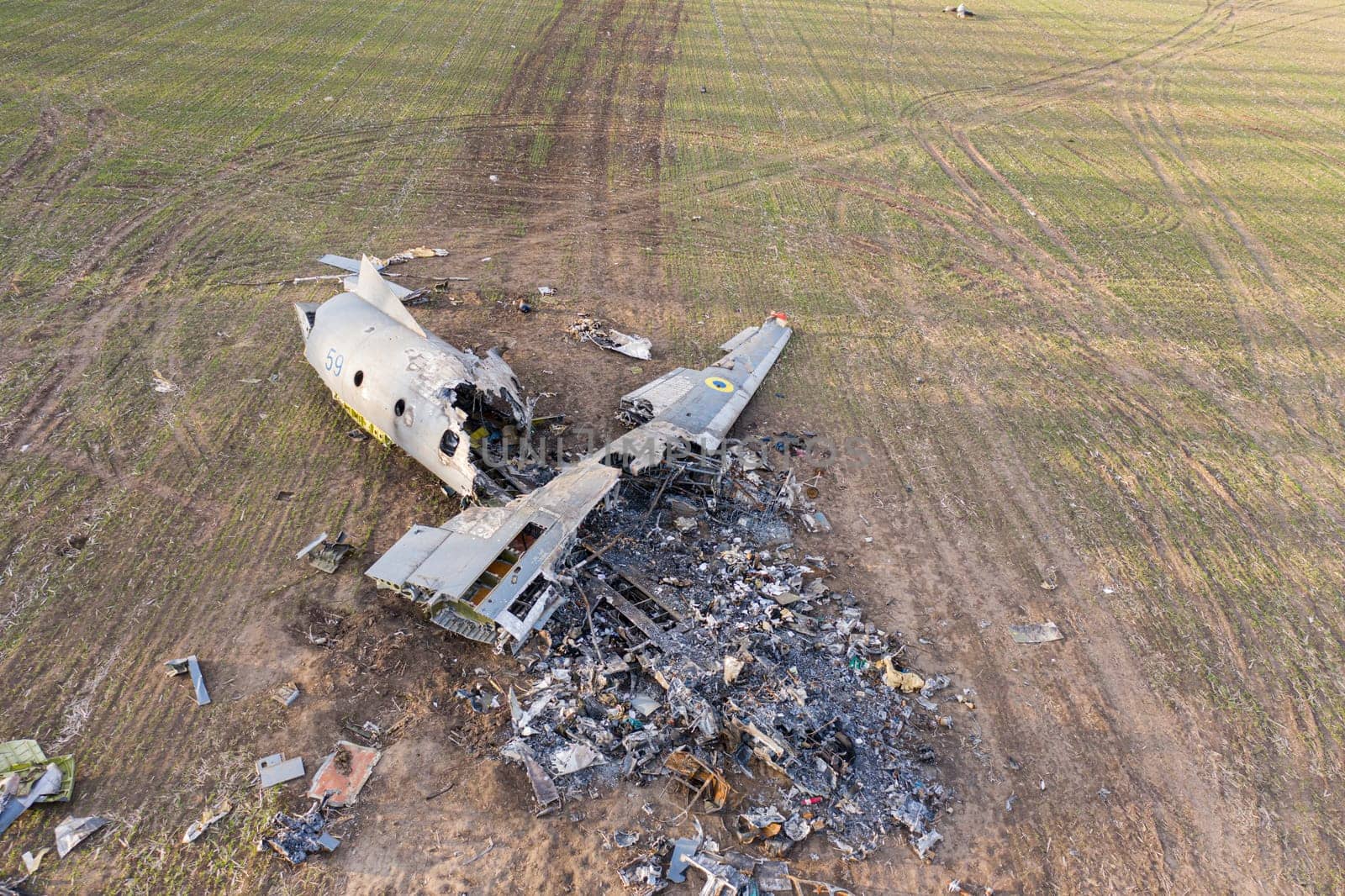 In this picture, an AN-26 aircraft can be seen lying on a field in Ukraine after an accident. The aircraft appears to have suffered significant damage, with parts scattered around the wreckage. The image conveys the severity of the accident and the potential dangers of aviation during the war