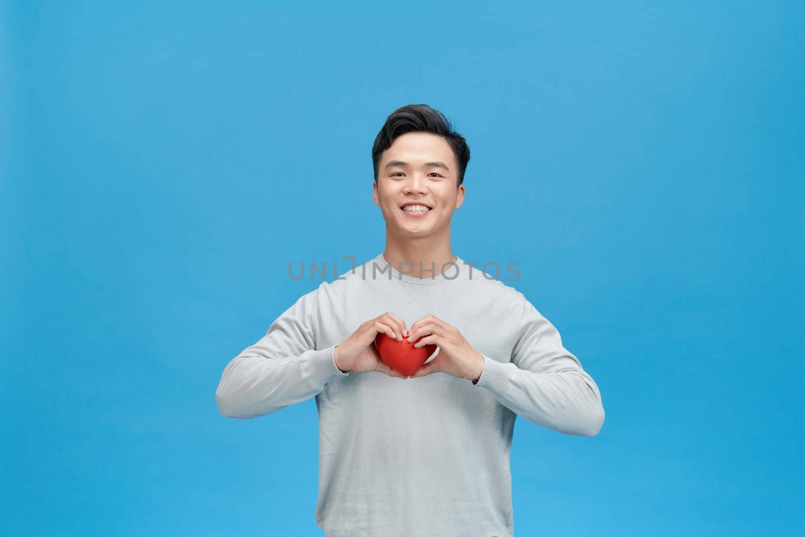 Young man holding a red heart shaped toy by makidotvn