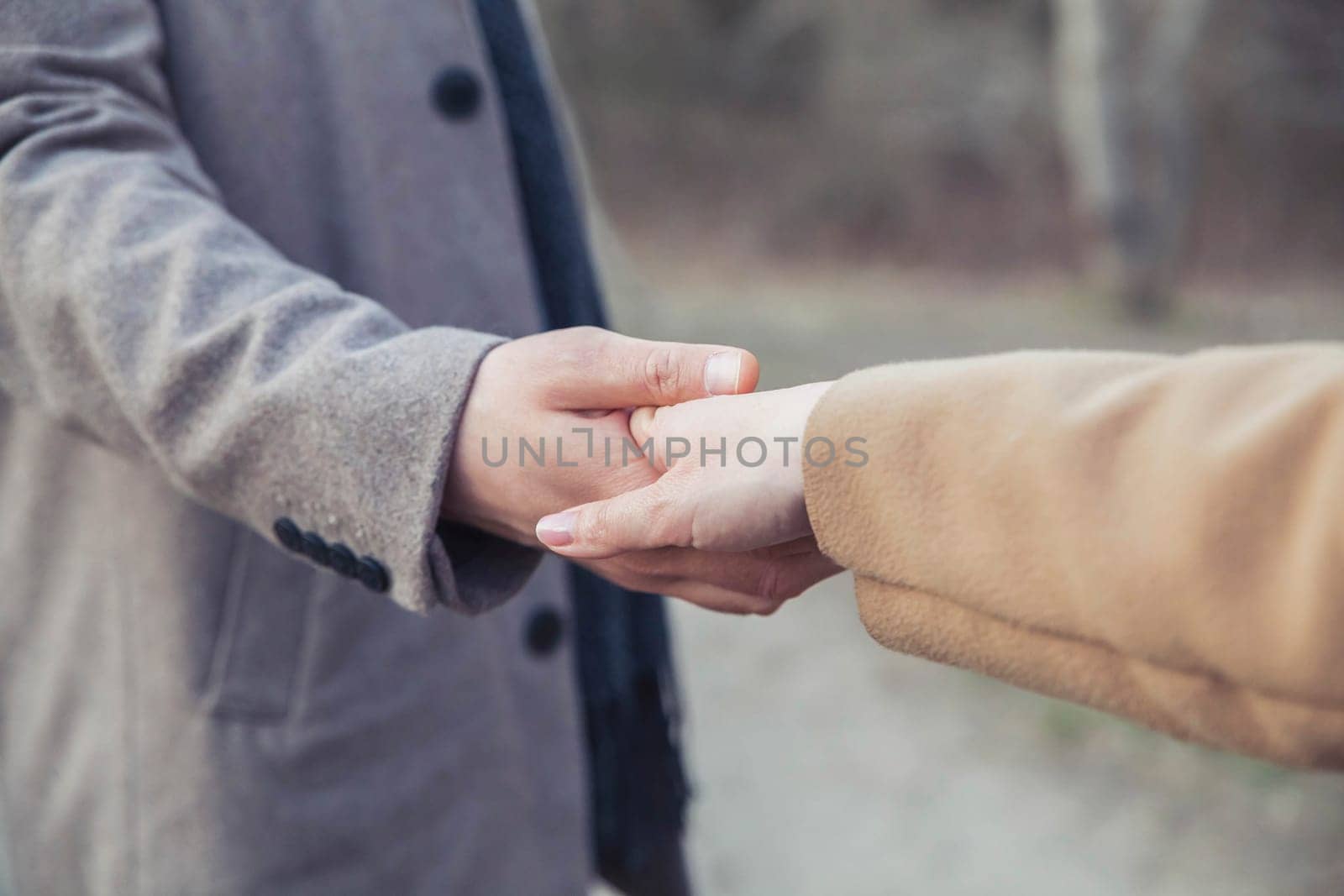 Married couple in coat holding hands in the park.