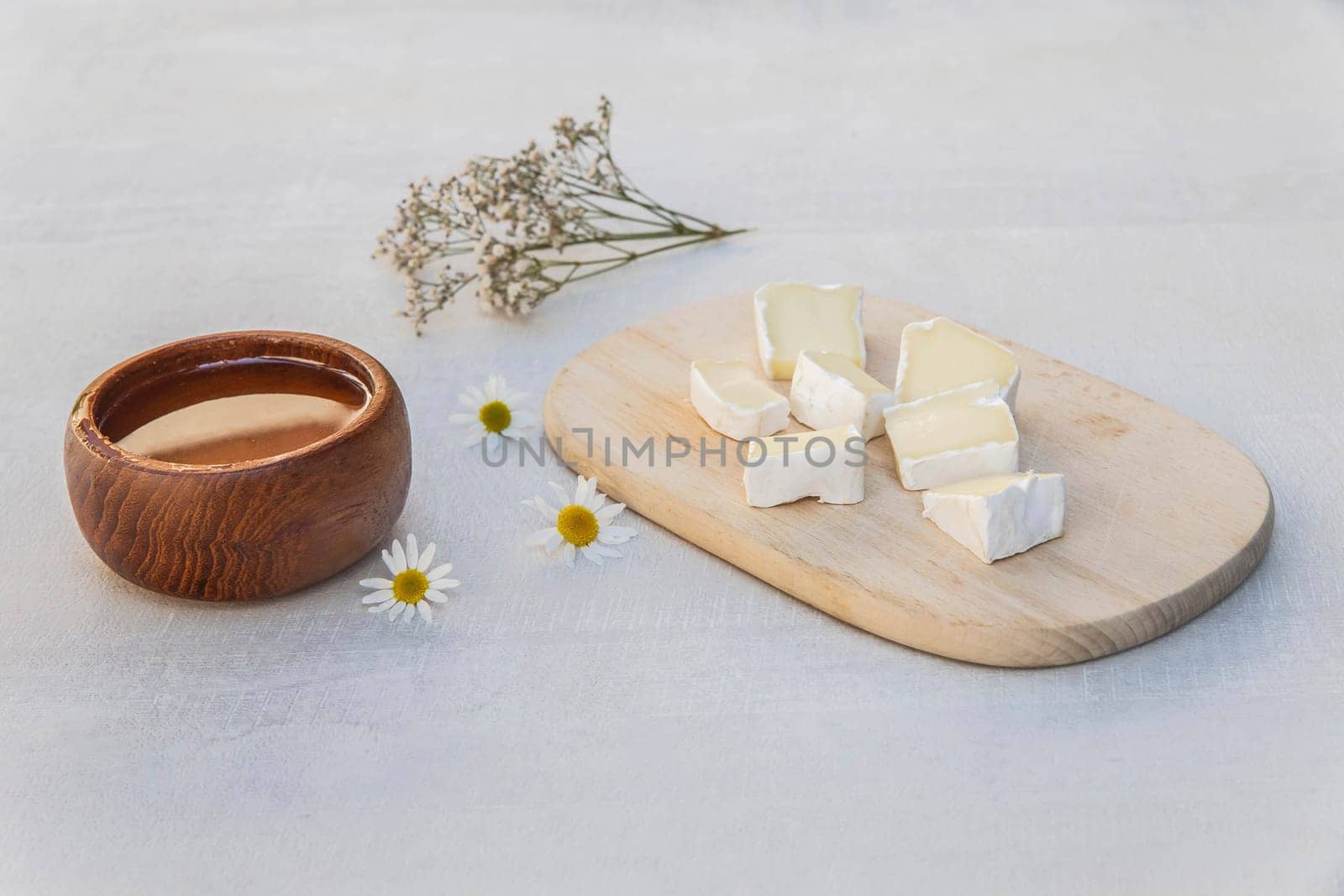 Blue cheese on a wooden plank, honey and flowers.