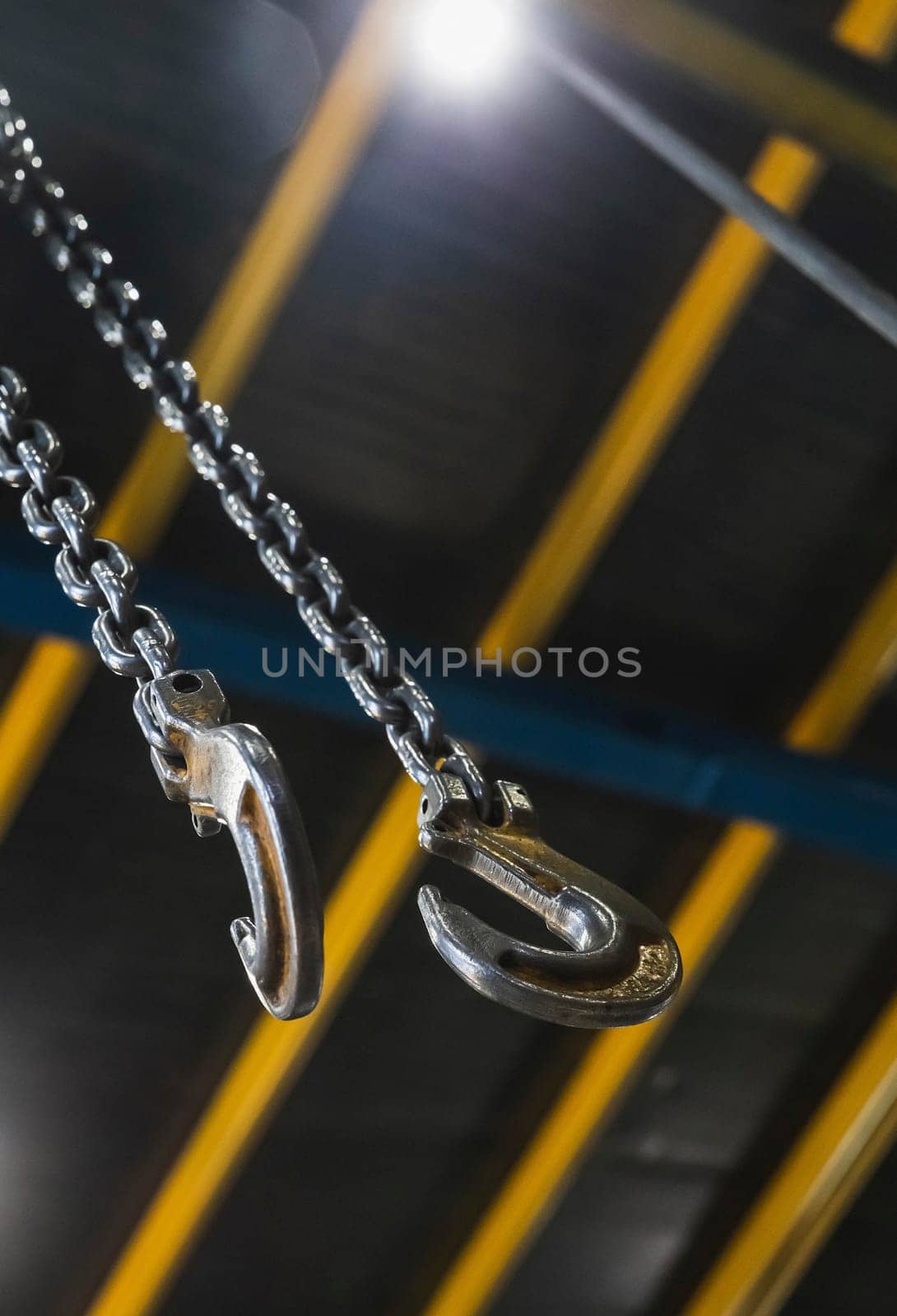 metal hook hanging on a chain in a factory focus on the hook.