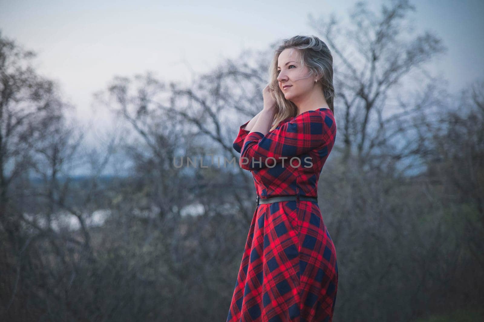 Attractive blonde girl in a red dress in the evening forest.