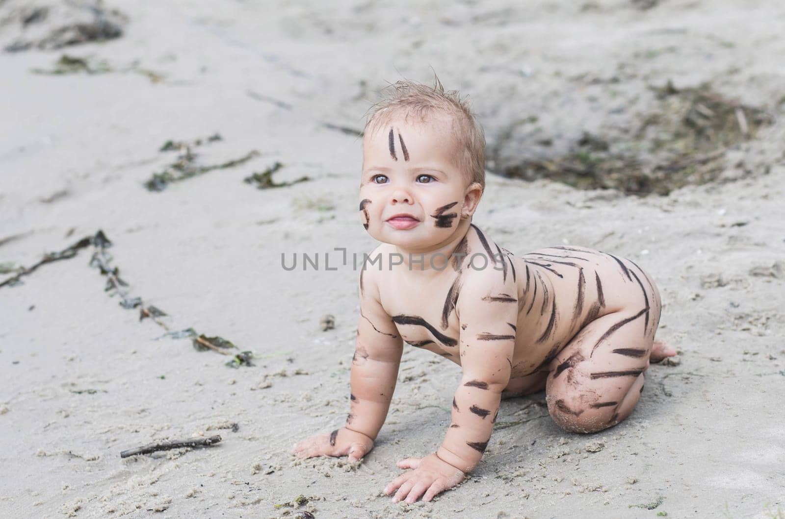 beautiful naked baby got dirty with mud walking on the beach.