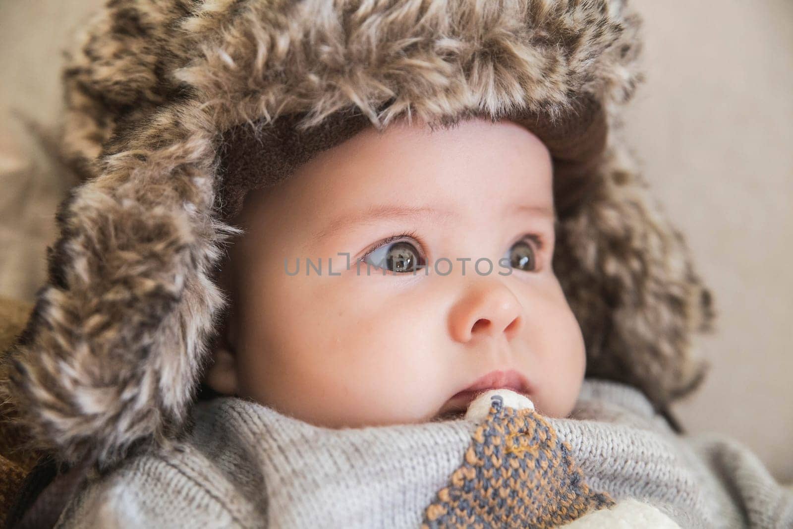 beautiful baby sitting in a fur hat.