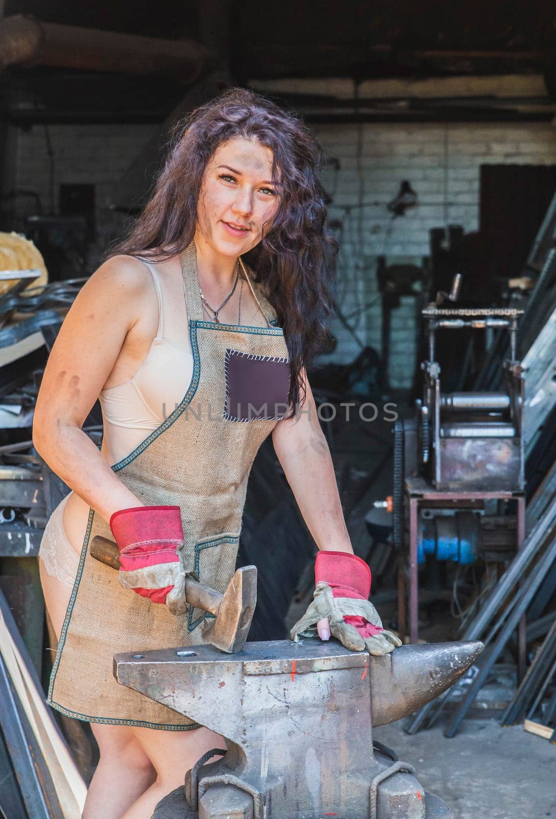 Blacksmith girl in the workshop near the anvil.