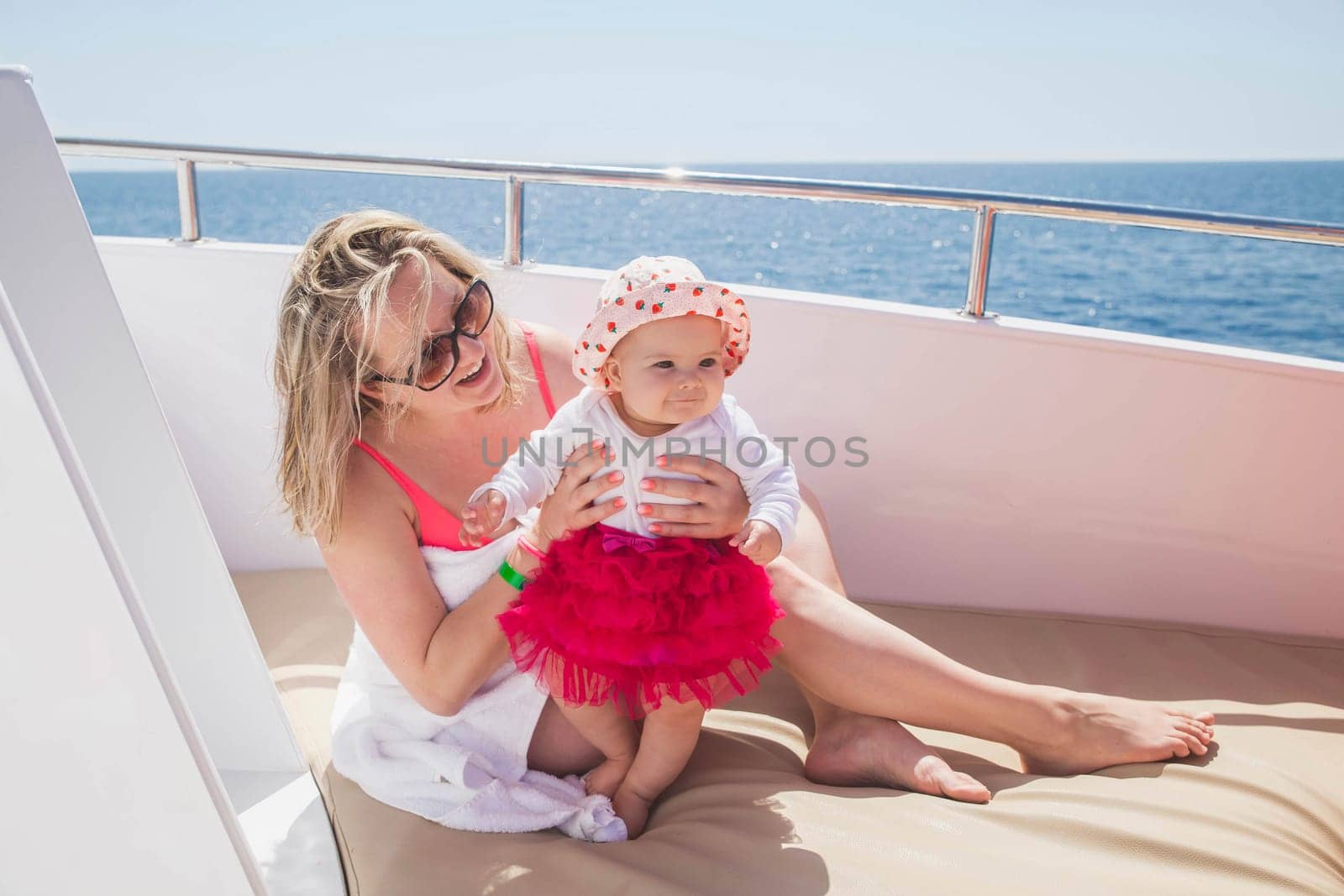 mom with newborn daughter sunbathe on a yacht in the sea.