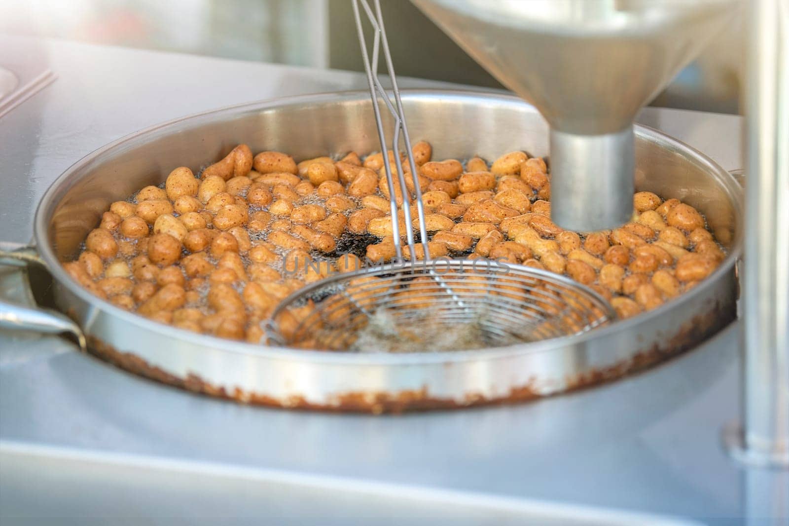 The process of cooking lokma, the cook cooks lokma in a deep fryer. Industrial production of a popular Middle Eastern dessert made from deep-fried dough balls. Little donuts. by SERSOL