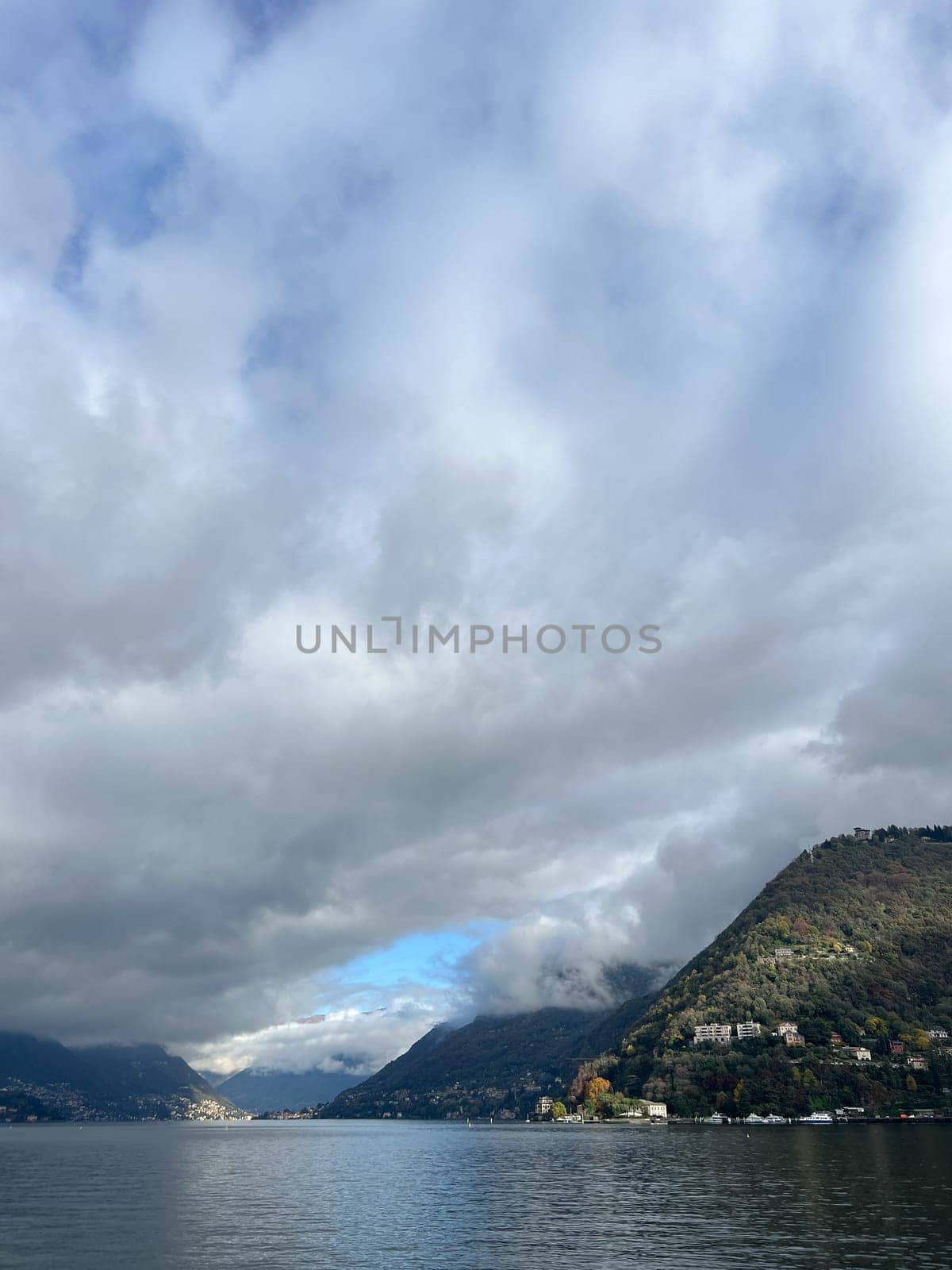 White cumulus clouds envelop a mountain range by the sea. High quality photo