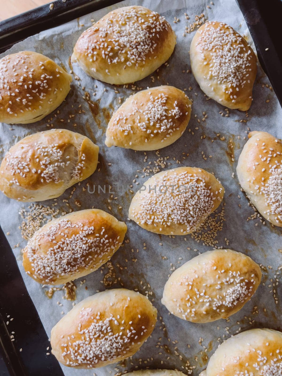 Freshly baked sesame buns lie on a baking sheet. High quality photo