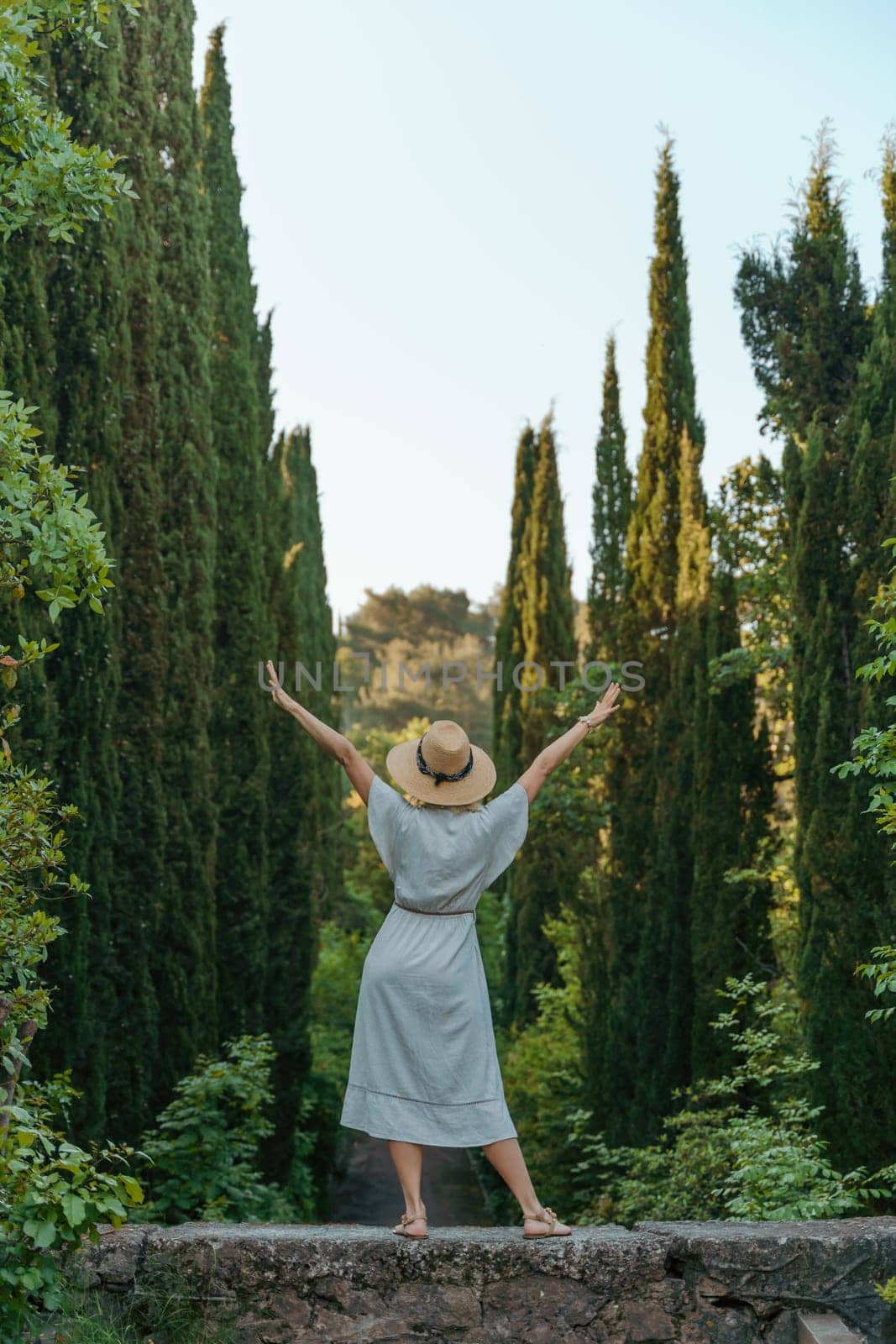 happy woman wearing a fedora hat while standing in the woods.