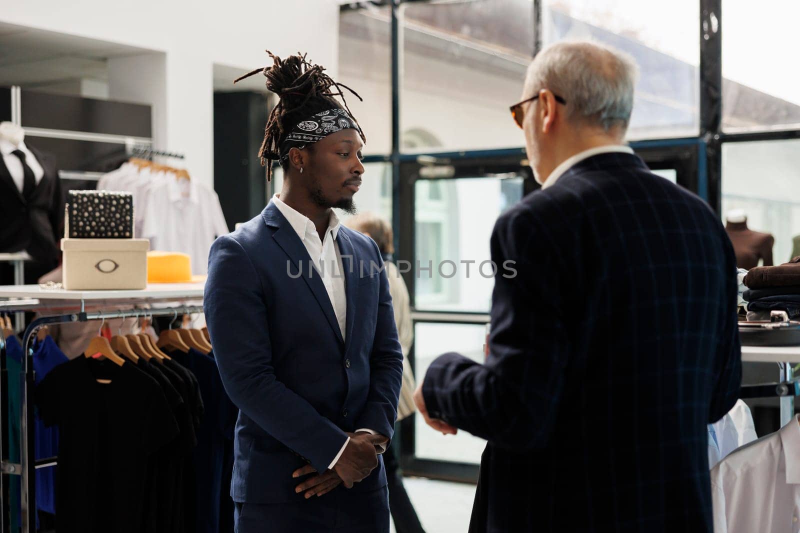 Stylish client discussing clothes fabric with store manager by DCStudio