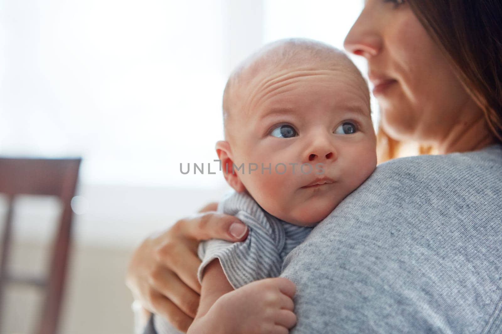 Calm and inquisitive. a mother holding her newborn baby. by YuriArcurs