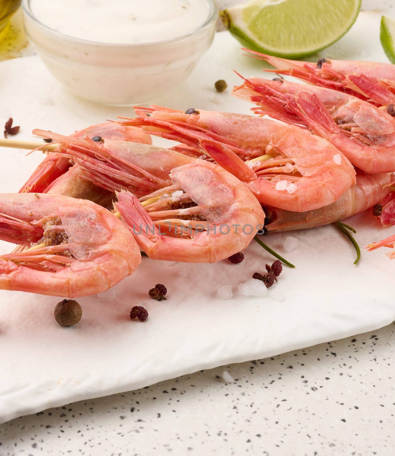 Shrimps strung on wooden sticks, soy sauce and spices on a white table, top view by ndanko