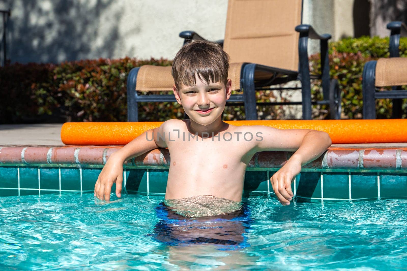 Oudoor summer activity. Concept of fun, health and vacation. Boy eight years old sits in a pool in hot summer day. by Marina-A