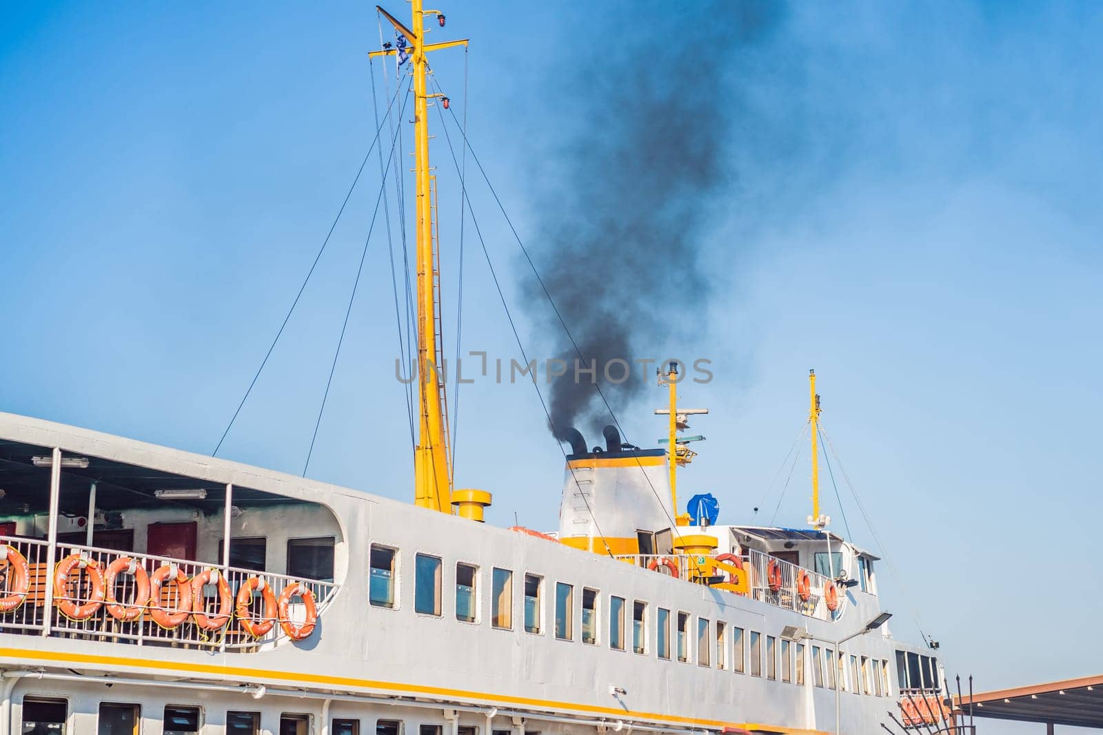 Ship polluting air with toxic smoke near a large city. Sulfur compound molecules are a big public health problem in populated areas, ports and airports.