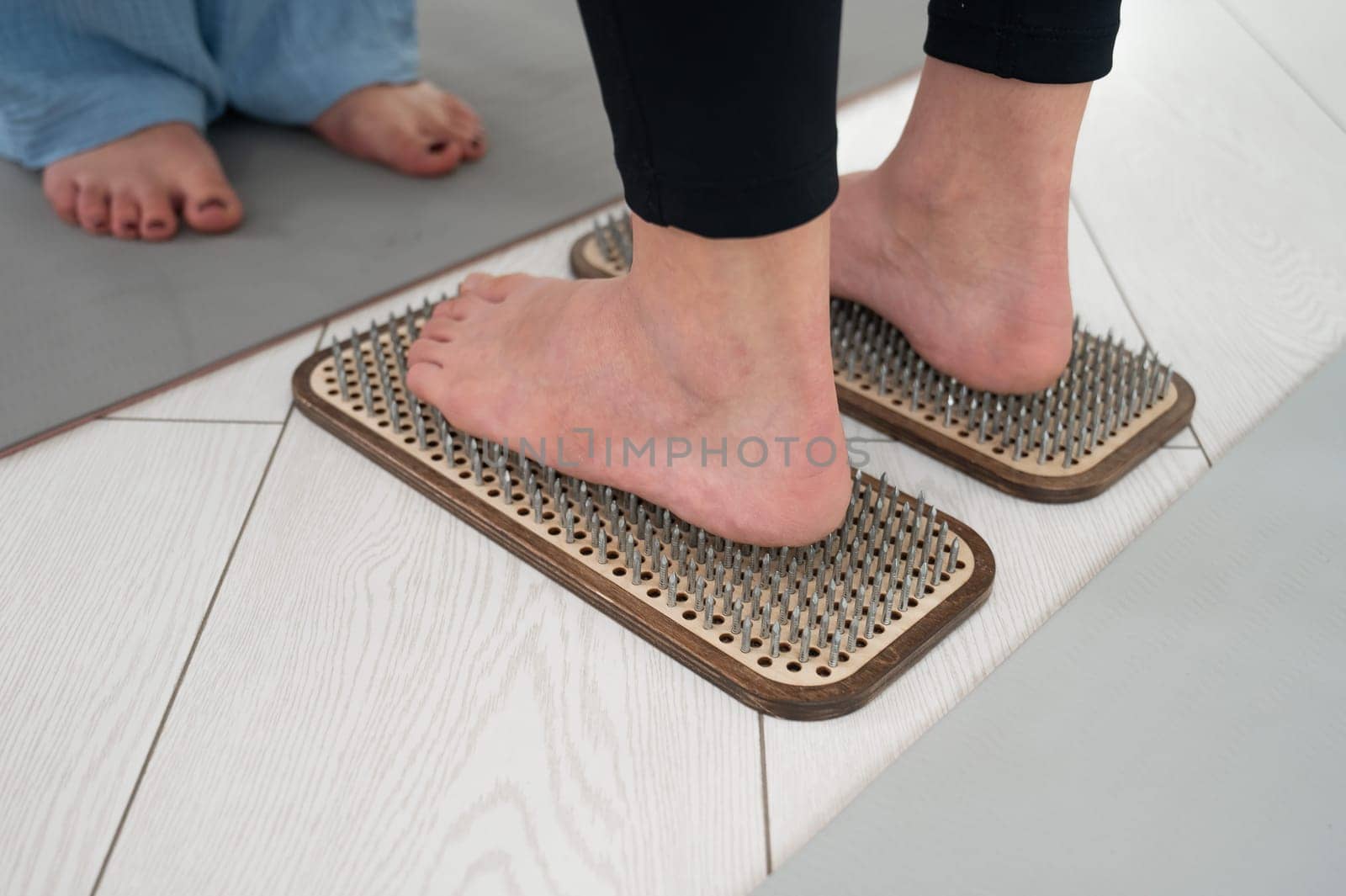 Caucasian woman stands on sadhu boards with therapist support