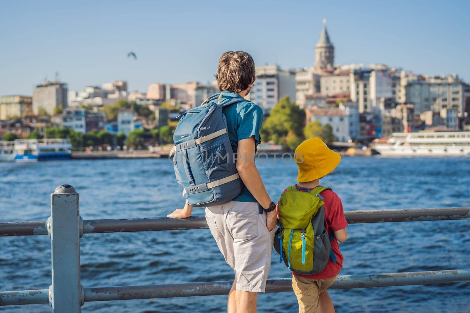 Father and son tourists enjoy Istanbul city skyline in Turkey, Beyoglu district old houses with Galata tower on top, view from the Golden Horn.