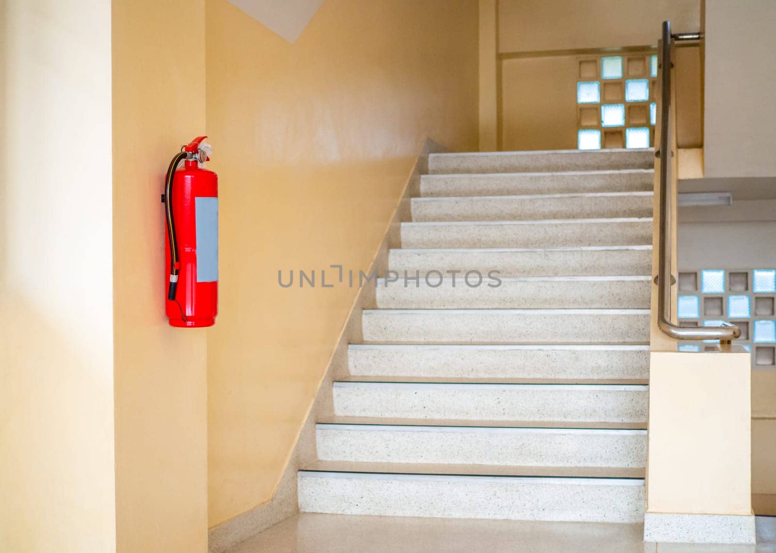 A fire extinguisher hangs up the stairs. Fire safety concept.