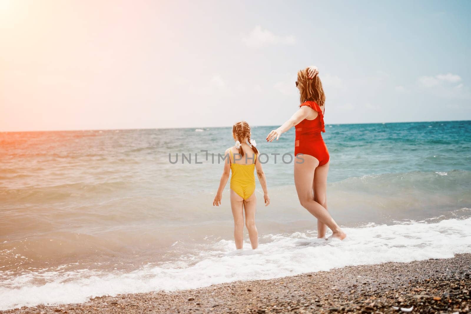 Happy loving family mother and daughter having fun together on the beach. Mum playing with her kid in holiday vacation next to the ocean - Family lifestyle and love concept by panophotograph