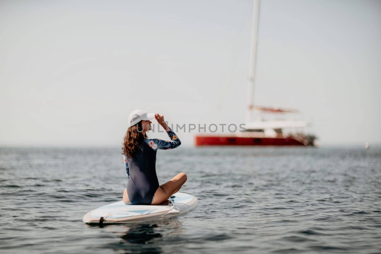 Woman sup yoga. Middle age sporty woman practising yoga pilates on paddle sup surfboard. Female stretching doing workout on sea water. Modern individual hipster outdoor summer sport activity