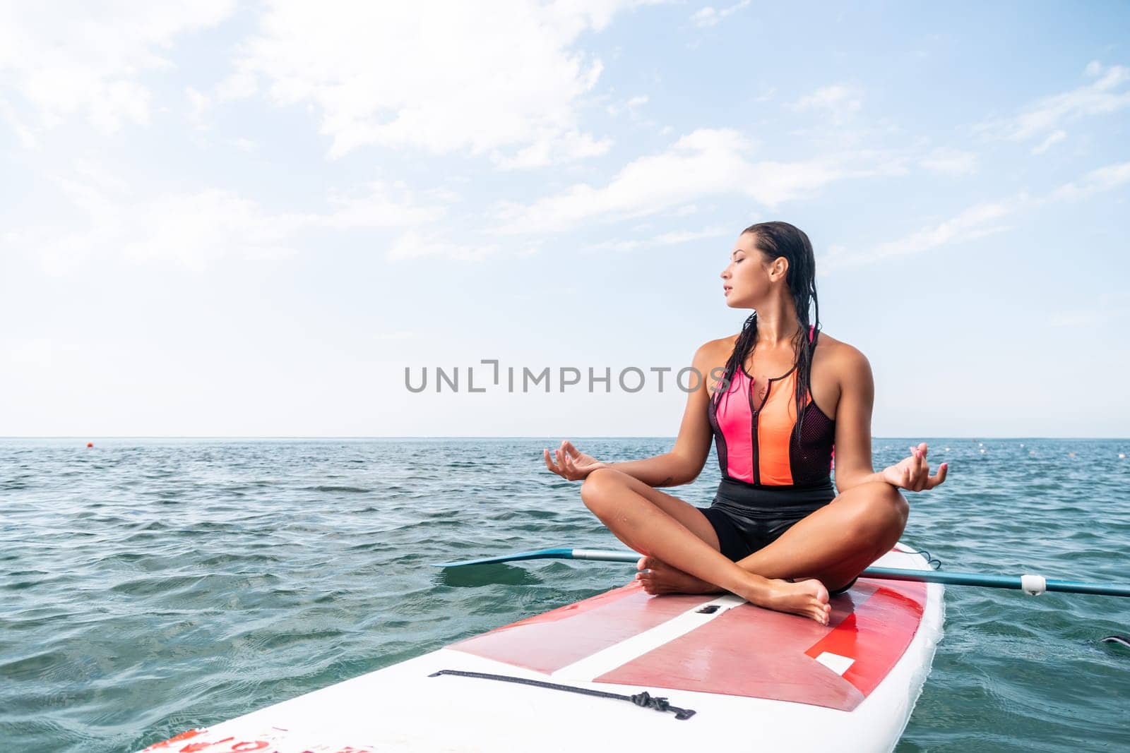 Woman sup yoga. Happy young sporty woman practising yoga pilates on paddle sup surfboard. Female stretching doing workout on sea water. Modern individual female outdoor summer sport activity